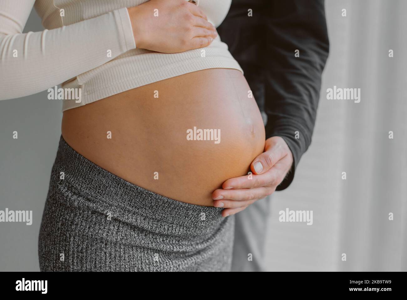 Couple expecting child baby bump man caressing pregnant woman stomach during pregnancy. Maternity shoot Stock Photo