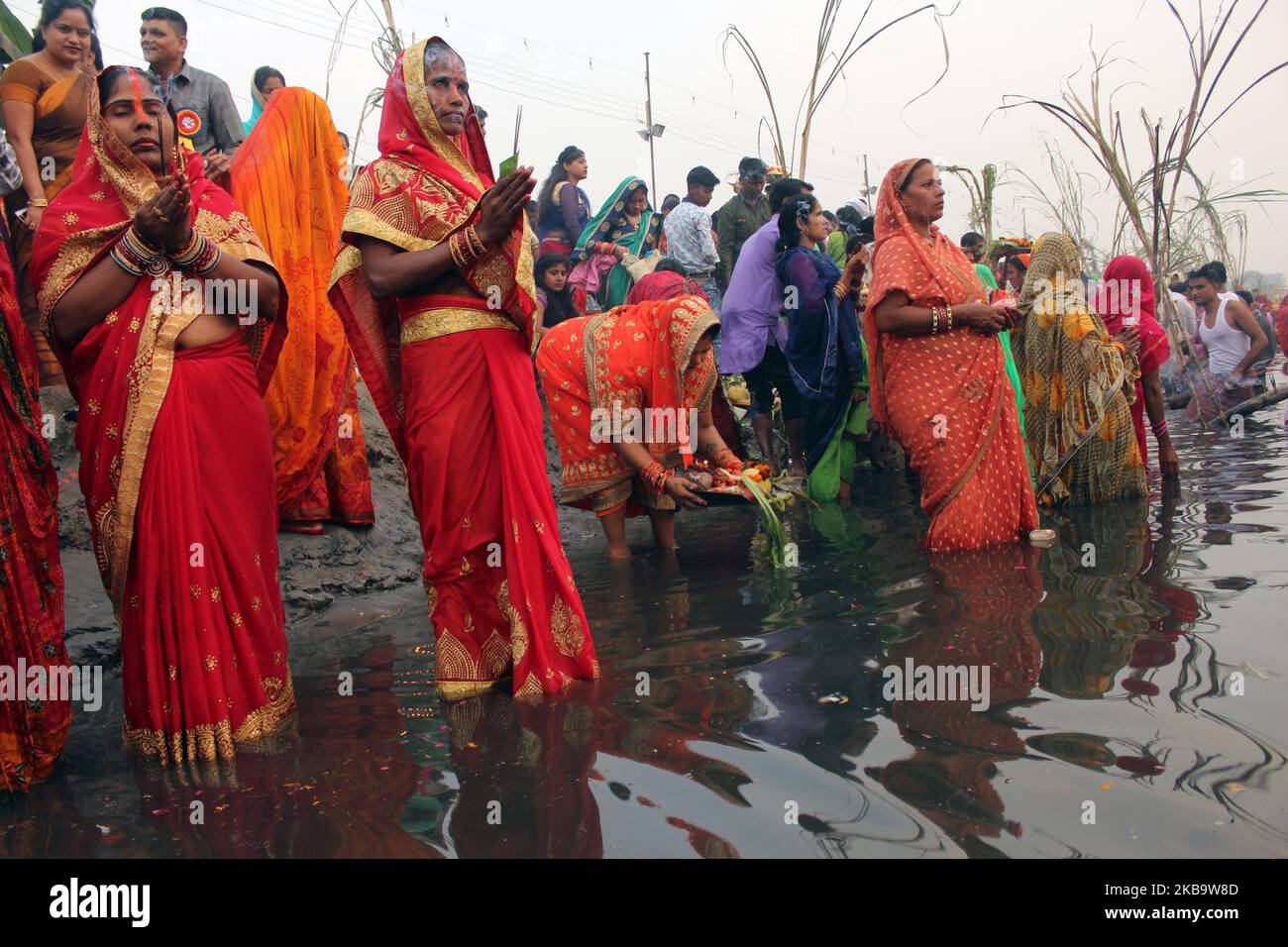 Hindu devotees are seen performing rituals and worshipping the Sun god along the banks of Yamuna River during the religious Hindu festival of Chhath Puja in New Delhi on November 13, 2018. The rituals involve taking dips in rivers or water bodies, strict fasting, standing and offering prayers in water, facing the sun for long periods and also offering Prasad to the sun at sunrise and sunset. (Photo by Mayank Makhija/NurPhoto) Stock Photo