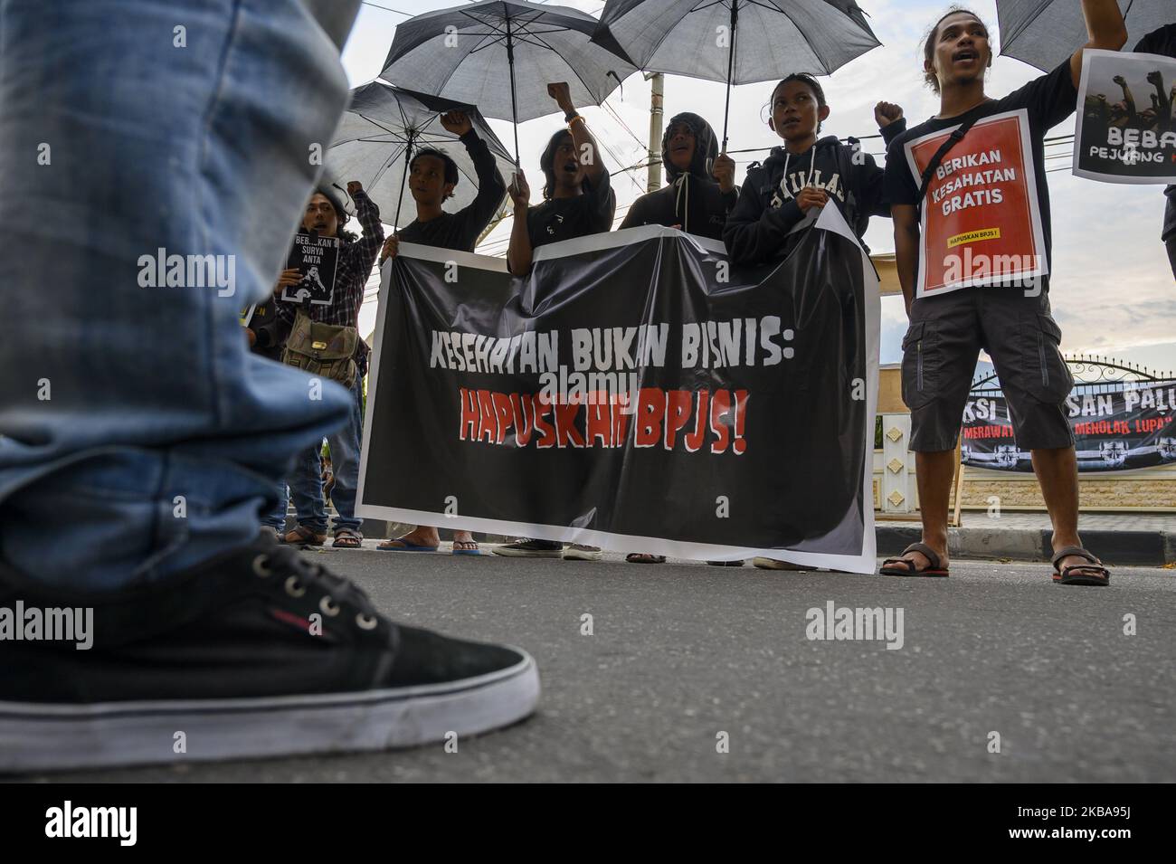 Humanitarian activists carry banners at the Kamisan Action in front of the Central Sulawesi House of Representatives Office in Palu, Central Sulawesi, Indonesia on November 7, 2019. The 16th Kamisan Action this time carries the theme of health and demands to the government so that the state can attend to any public health issues and reject the increase in health insurance contributions managed by the state because they are considered burdening the people. (Photo by Basri Marzuki/NurPhoto) Stock Photo