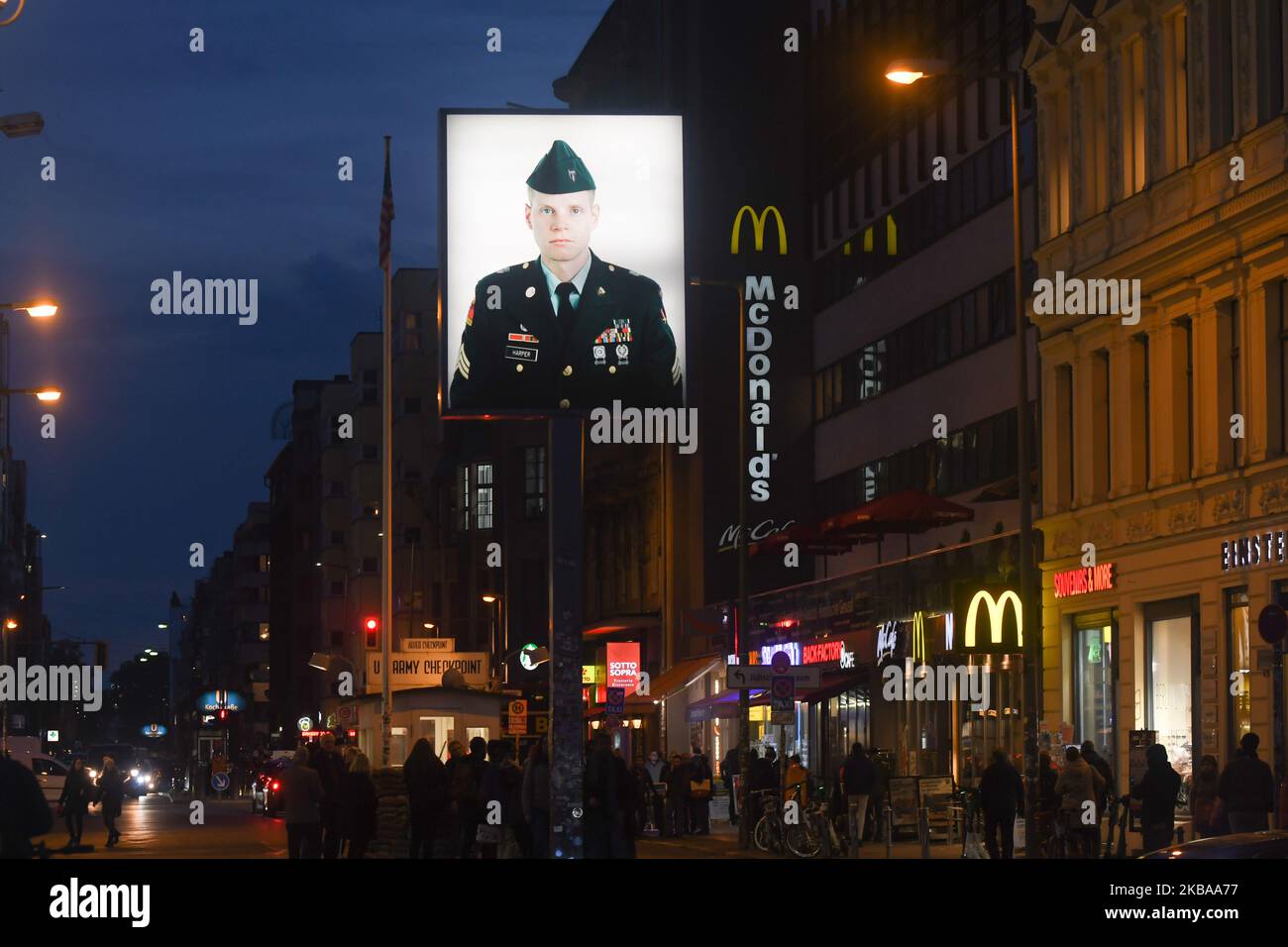 A portrait of a U.S. soldier stands illuminated at former Checkpoint Charlie, where U.S. and Soviet tanks confronted each other in the early years of the Cold War, seen just two days ahead of the upcoming 30th anniversary of the fall of the Berlin Wall. The Berlin Wall divided the German capital from 1961 until 1989. Checkpoint Charlie was a main crossing point at the Wall from the American Sector in West Berlin into the Russian sector in East Berlin. On Thursday, November 7, 2019, in Berlin, Germany. (Photo by Artur Widak/NurPhoto) Stock Photo
