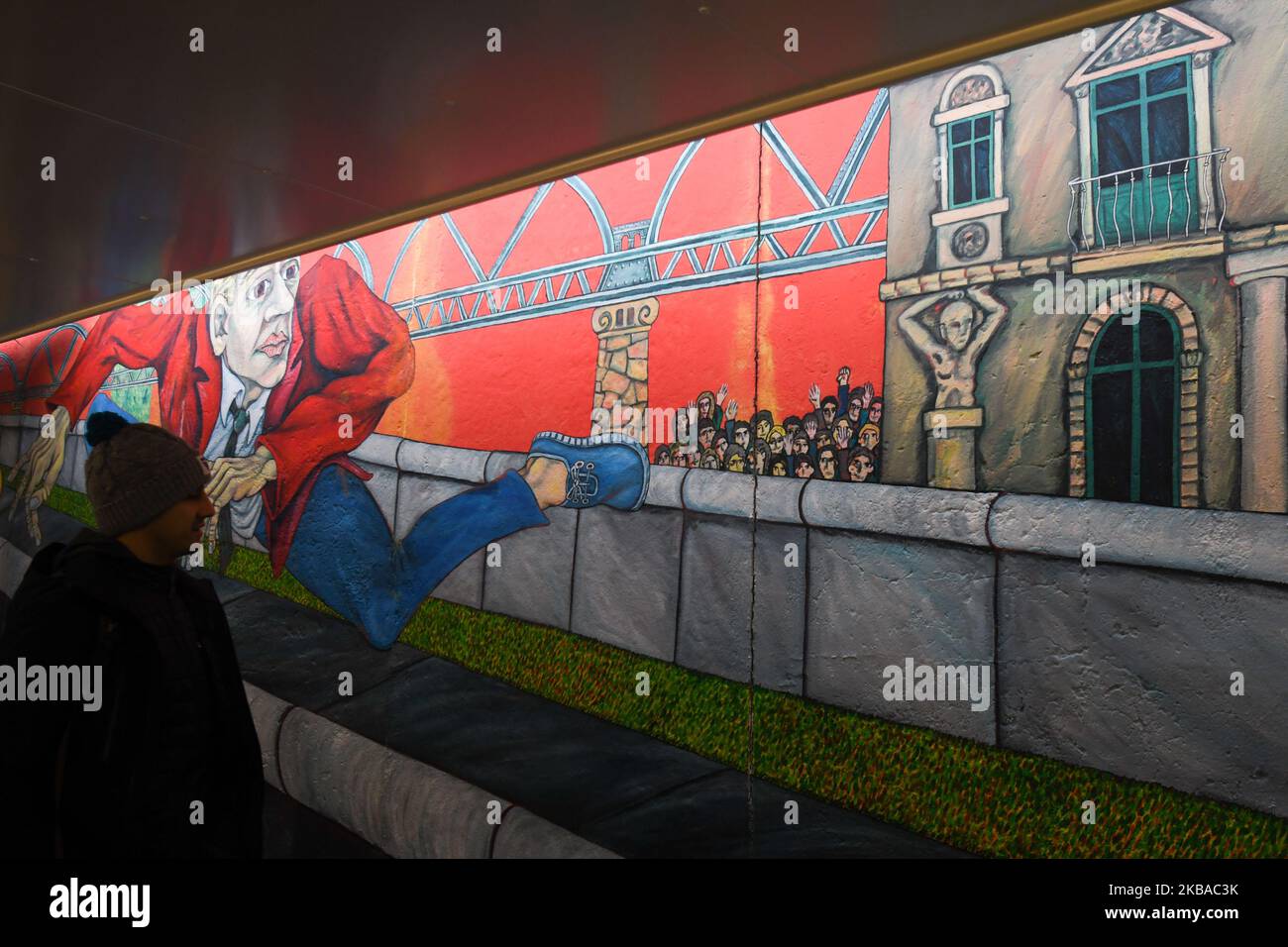 A visitor walks by a mural ‘Der Mauerspringer’, (‘The Wall Jumper’), painted by Gabriel Heimler, a part of a still-standing section of the former Berlin Wall called the East Side Gallery, on the eve of the upcoming 30th anniversary of the fall of the Berlin Wall. Germany marks three decades since the fall of the Berlin Wall this week with main celebrations in the German capital on Saturday, November 9, 2019. On Friday, November 8, 2019, in Berlin, Germany. (Photo by Artur Widak/NurPhoto) Stock Photo