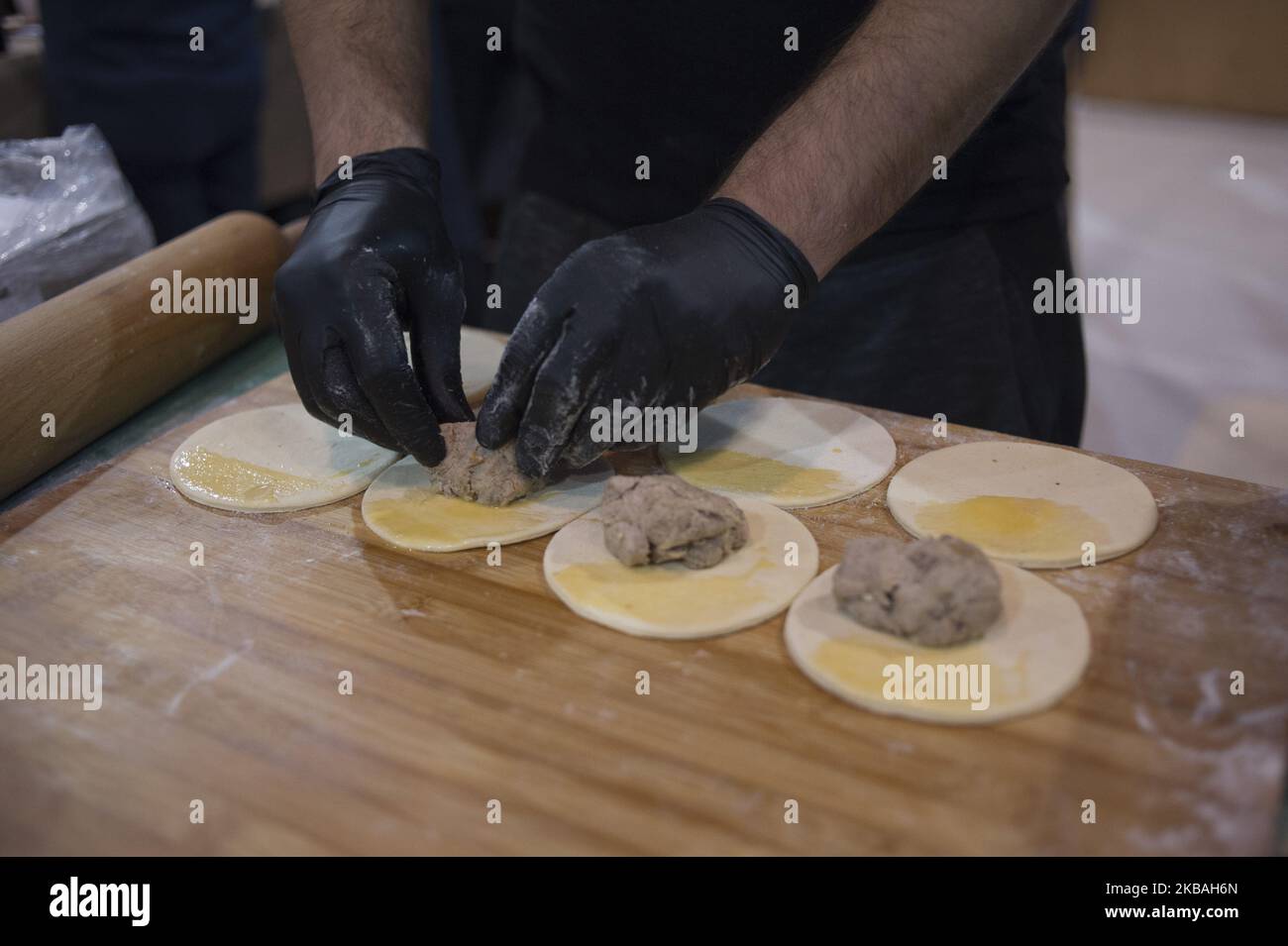 A cook fills the Cepelinai dough with ground meet during the world's dumplings festival in Warsaw, Poland on November 09, 2019. (Photo by Aleksander Kalka/NurPhoto) Stock Photo