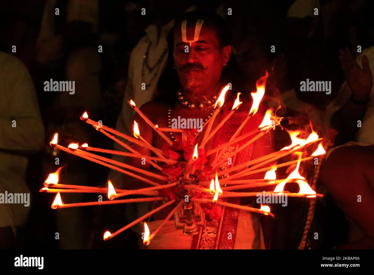 A Hindu priest holds a traditional lamp as he performs evening prayers
