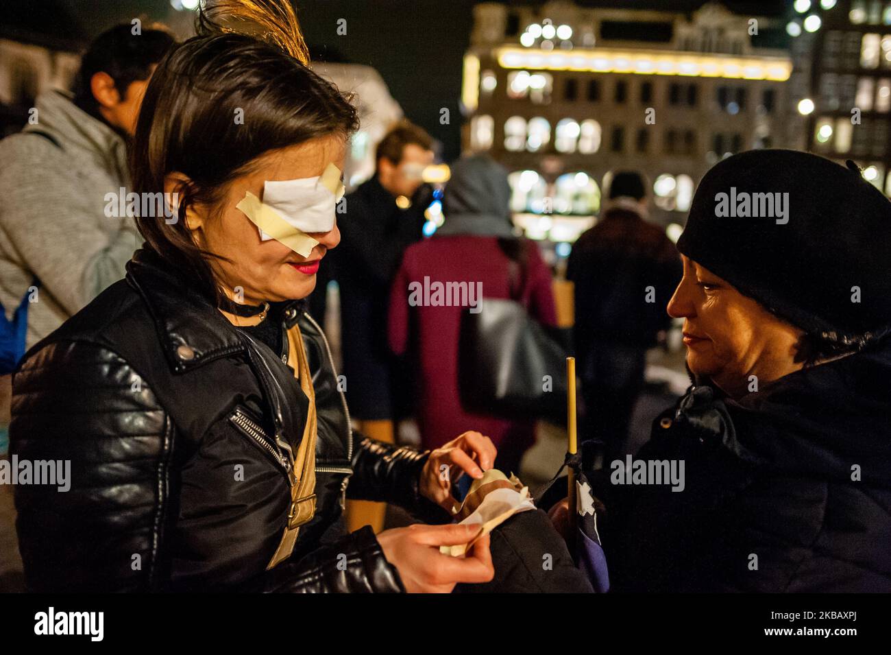 A woman is helping to another woman to put an eye patch before the Remembrance for the Murder of Camilo Catrillanca started, in Amsterdam, on November 14th, 2019. (Photo by Romy Arroyo Fernandez/NurPhoto) Stock Photo