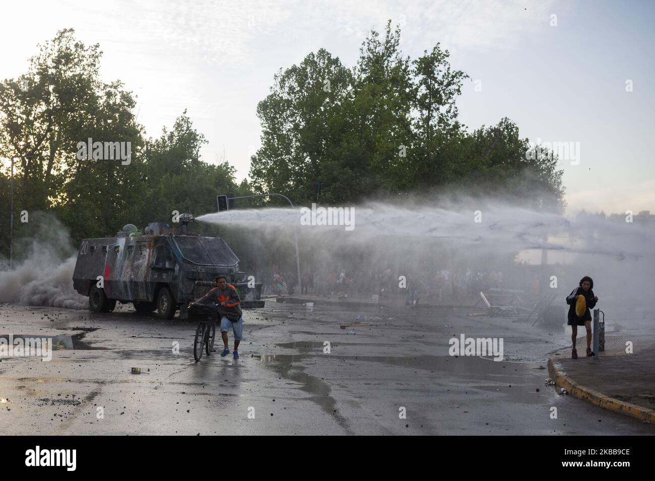 An anti-government demonstrator challenges a police water cannon spray during clashes with police in Santiago, Chile, Thursday, October 30, 2019. (Photo by Jeremias Gonzalez/NurPhoto) Stock Photo