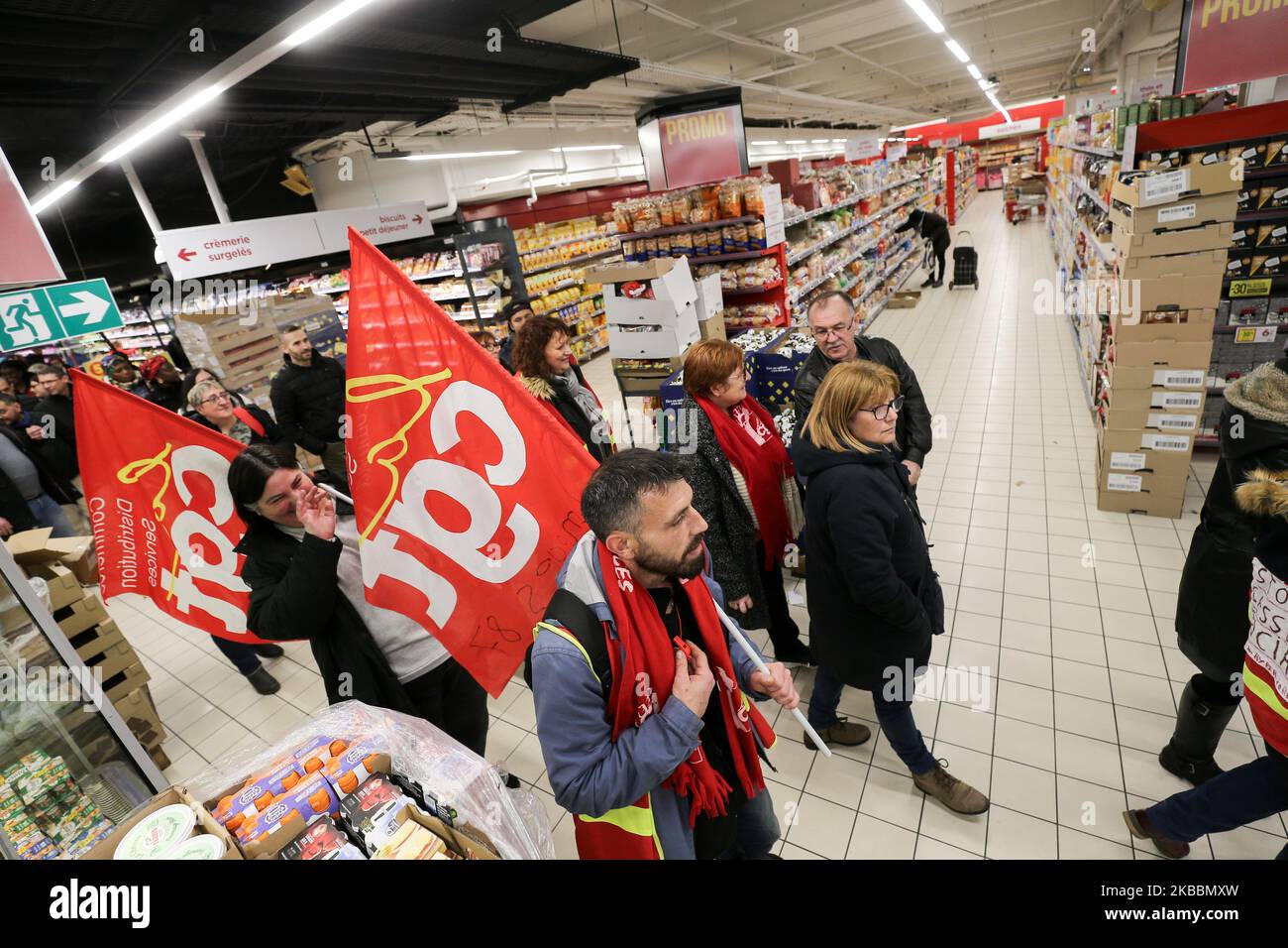 French General Confederation of Labour (CGT) union members holding flags walk inside Casino supermarket in the 13th arrondissement of Paris on November 26, 2019, during a demonstration against the deterioration in working conditions and the take over by the German group Aldi of 700 Leader Price stores, one of the group's subsidiaries.The Casino Group confirmed on September 19, 2019, the existence of discussions with the Aldi France group concerning the acquisition of Leader Price. (Photo by Michel Stoupak/NurPhoto) Stock Photo
