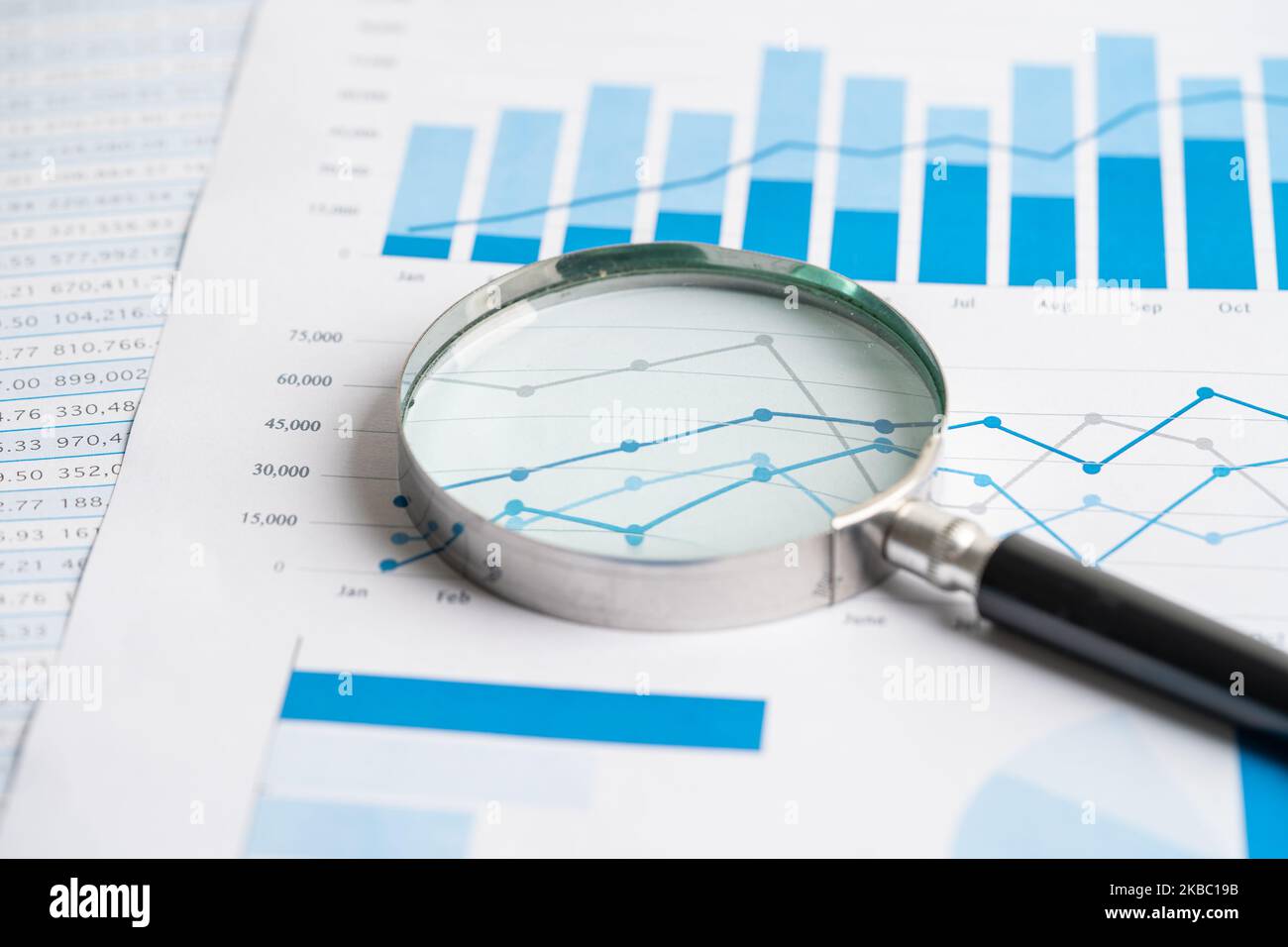 Magnifying glass on chart graph spreadsheet paper. Financial ...