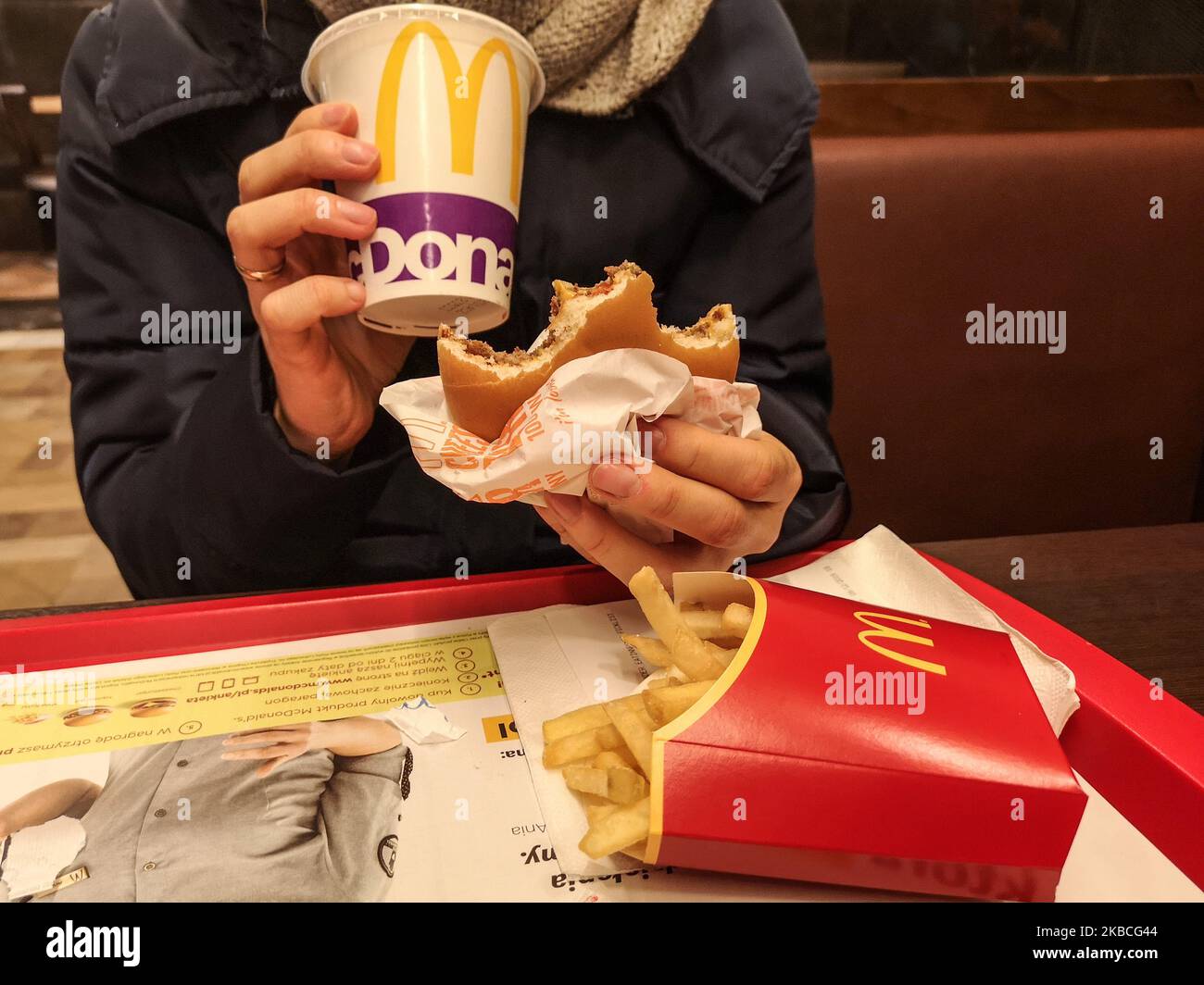 Woman eating fast food meal (cheeseburger , chips and Coca Cola) in McDonald's restaurant is seen in Gdynia, Poland on 9 December 2019 (Photo by Michal Fludra/NurPhoto) Stock Photo