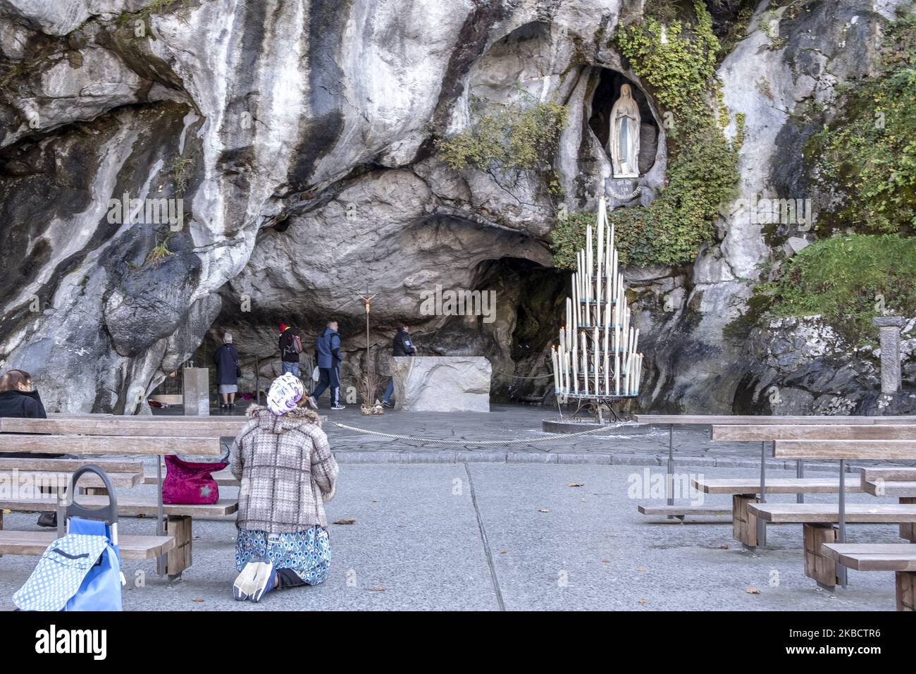 A woman prays kneeling before the cave where the virgin allegedly appeared to the little shepherdess on November 30, 2019 in Lourdes, France. The Pope stops the business of miracles in LourdesFrancisco intervenes the sanctuary and sends a delegate to recover the spiritual side of the place, buried by its commercial and tourist side. Lourdes receives two and a half million visits a year. It is a tourism that has faith as a claim and that has transformed a whole valley that lives on pilgrims. (Photo by Alvaro Fuente/NurPhoto) Stock Photo