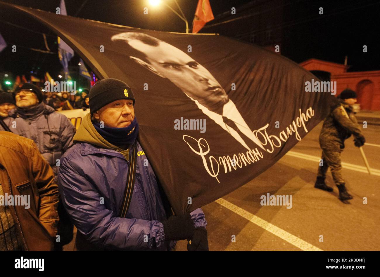 Ukrainians carry a banner with Stepan Bandera portrait during a torchlight procession dedicated to the 111th of Stepan Bandera birthday in center of Kyiv, Ukraine, on 1 January 2020. Members and supporters of 'Svoboda' ('Freedom') nationalistic party attended the torch march to mark leader and ideologist of Ukrainian national movement Stepan Bandera birthday. (Photo by STR/NurPhoto) Stock Photo