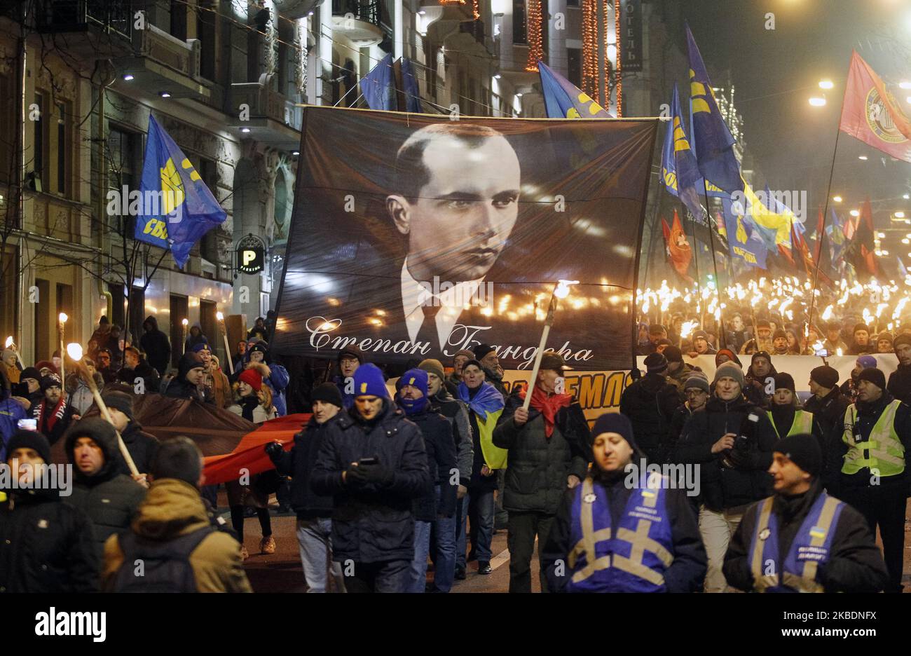 Ukrainians carry a banner with Stepan Bandera portrait during a torchlight procession dedicated to the 111th of Stepan Bandera birthday in center of Kyiv, Ukraine, on 1 January 2020. Members and supporters of 'Svoboda' ('Freedom') nationalistic party attended the torch march to mark leader and ideologist of Ukrainian national movement Stepan Bandera birthday. (Photo by STR/NurPhoto) Stock Photo