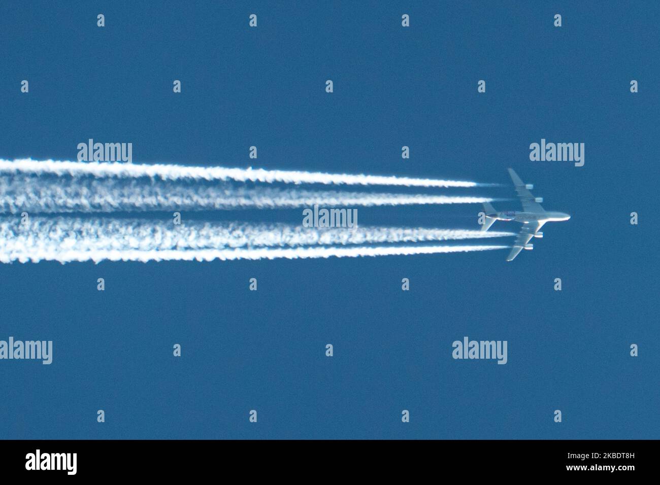 An airline commercial aircraft overflying in the blue sky long contrails of condensation behind it at very high altitude of 40.000 feet. The airliner is an Etihad Airways wide-body, long haul double-decker Airbus A380 airplane with registration A6-APC flying from Abu Dhabi, United Arab Emirates AUH to London Heathrow LHR airport in England, UK. ETIHAD logo is visible on the belly of the fuselage of the jetliner The overfly plane is above Maastricht city in The Netherlands, coming from Germany and entering the airspace of Belgium in a few minutes. (Photo by Nicolas Economou/NurPhoto) Stock Photo