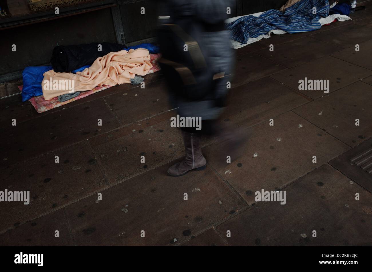 People walk past the bedding and belongings of rough sleepers outside