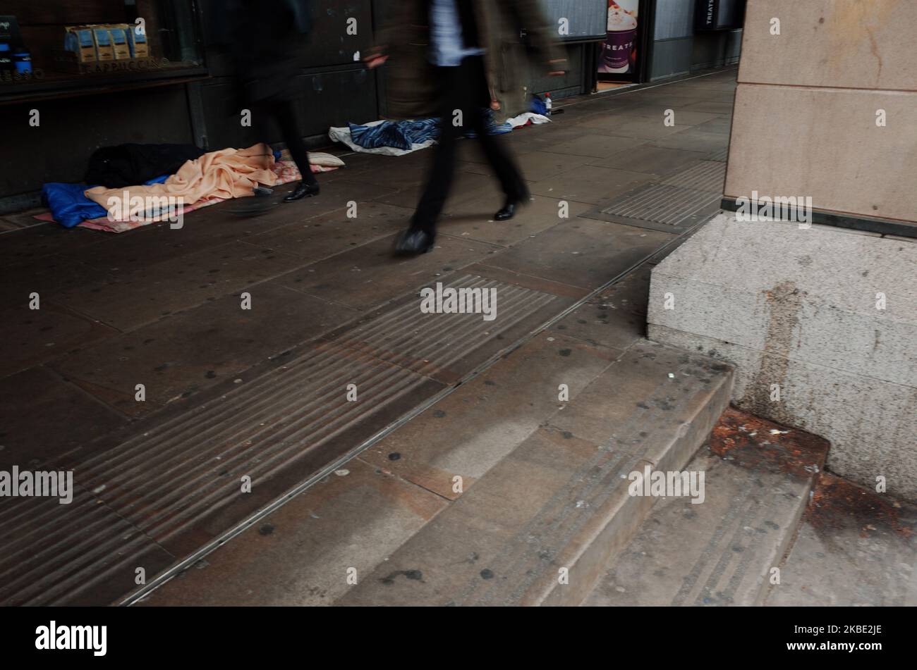 People walk past the bedding and belongings of rough sleepers outside