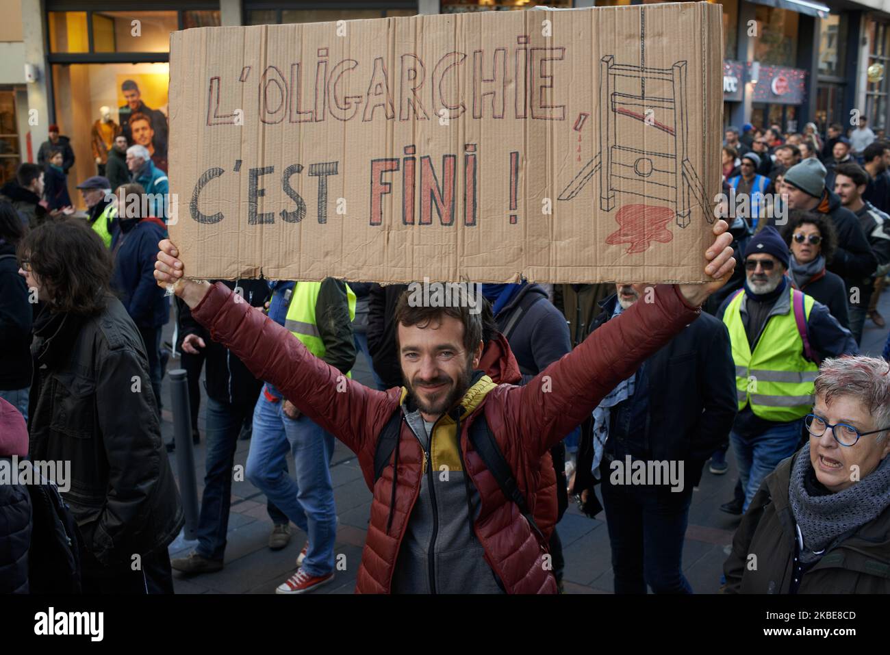 A protester holds a placard reading 'This is the end for the oligarchy'. Yellow Vests protesters demonstrated for more than 60 weeks in a row across France. Several thousands protesters took to the streets of Toulouse. They also protested against the Macron's planned reform on retirement. But the peaceful protest came to a sudden end as riot police and fired water cannon and fired tear gas canisters. Toulouse. France. January 11th 2020. (Photo by Alain Pitton/NurPhoto) Stock Photo
