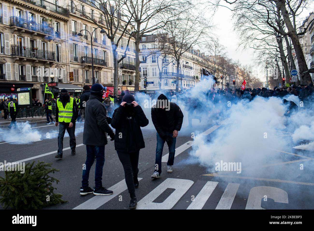 Demonstrators surrounded by tear gas during the clashes that broke out along the demonstration against the pension reform project. The inter-union organization made up of CGT, FO, Solidaires unions, SUD, FSU and student organizations, called for a new day of action against the pension reform and 38th day of strike. Paris, France, 11 janvier 2020. Des manifestants au milieu des gaz lacrimogene lors des heurts qui ont eclate le long de la manifestestion contre le projet de reforme des retraites. L'organisation intersyndicale composee de la CGT, FO, des syndicats Solidaires, SUD, FSU et des organ Stock Photo