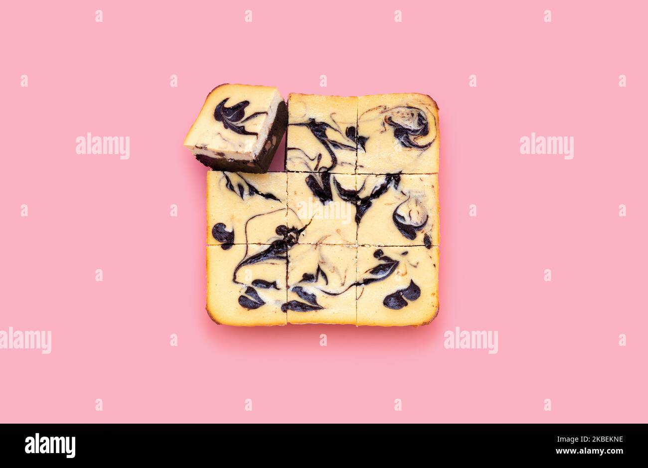 Homemade brownie cheesecake minimalist on a pink-colored background. Top view with a delicious layered cake with a chocolate layer and cream cheese. Stock Photo