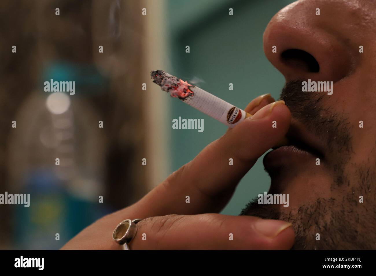 A man smokes Gold Flake Cigarette outside a restaurant in New Delhi