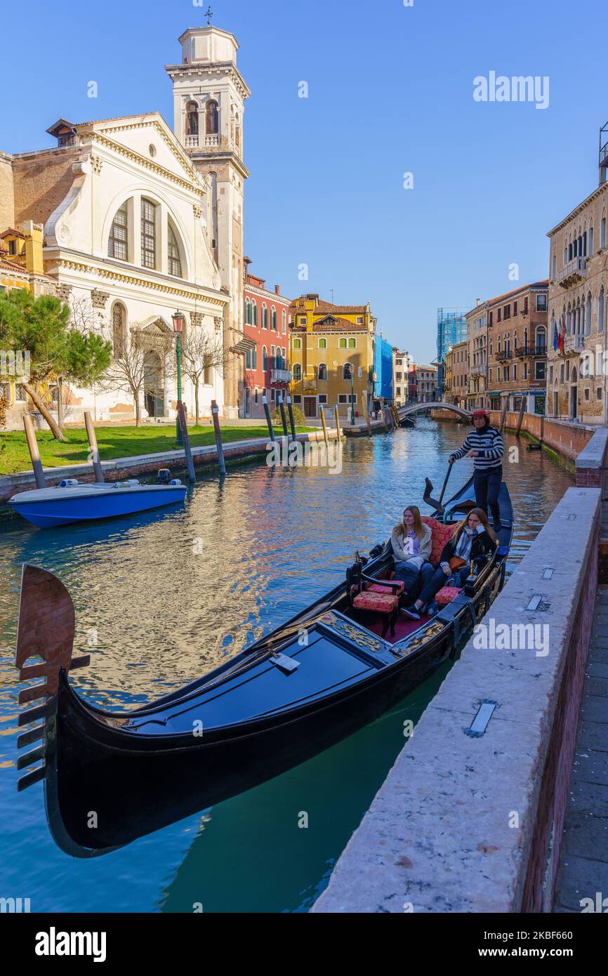 Venice, Italy - March 01, 2022: View of the San Trovaso canal and church, with gondola, gondolier, and passengers, in Venice, Veneto, Northern Italy Stock Photo