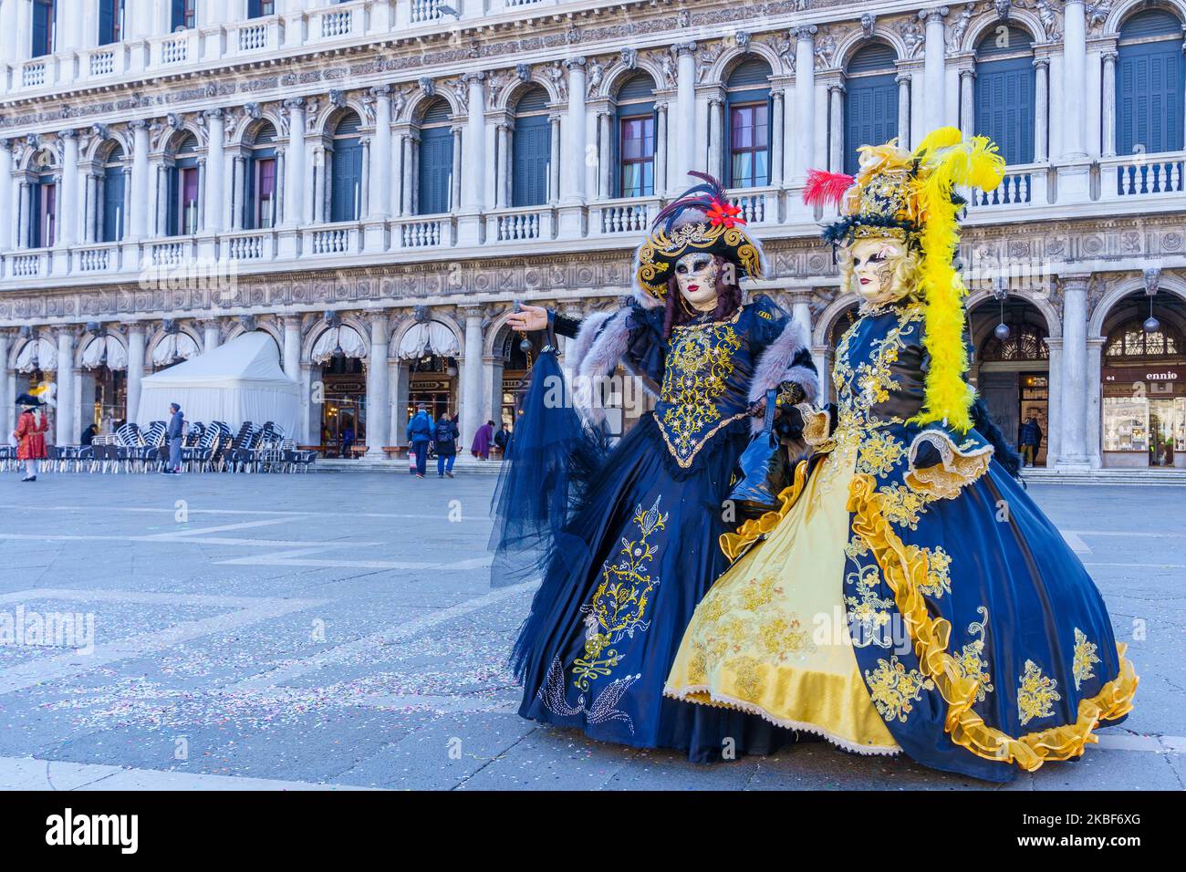 Venice, Italy - March 01, 2022: Couple dressed in traditional costumes stand in front of the Ducal palace, part of the Venice Mask Carnival, Veneto, I Stock Photo