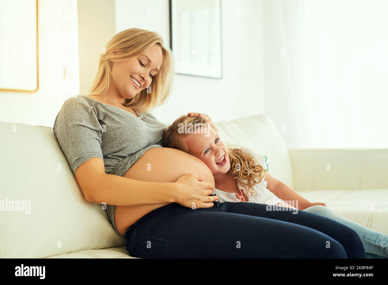 Bonding with her baby brother. a little girl listening to her mothers pregnant belly. Stock Photo