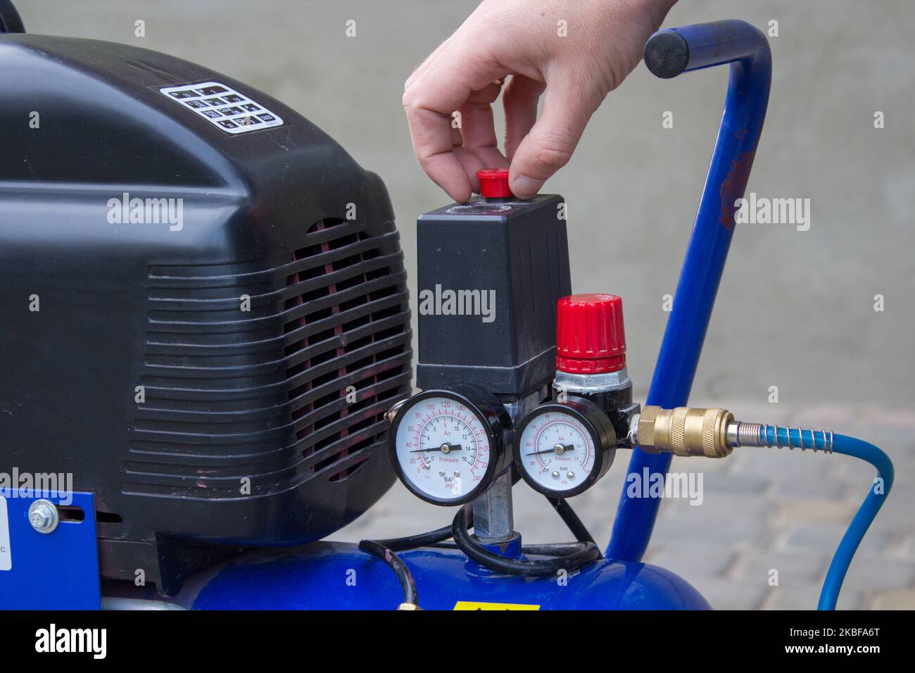 Starting the air compressor with your hand in the yard Stock Photo