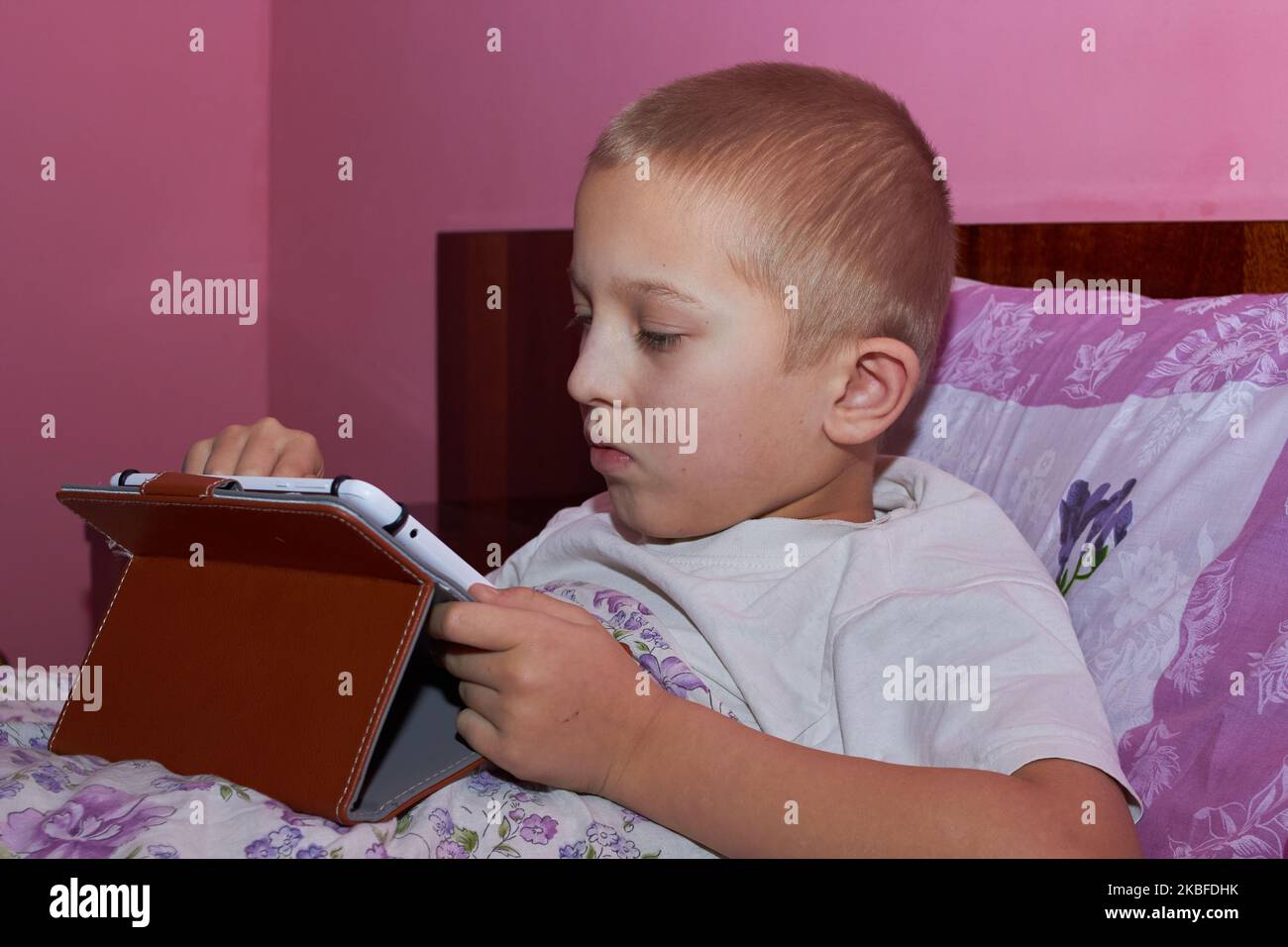 boy lying in bed with a tablet playing online games Stock Photo