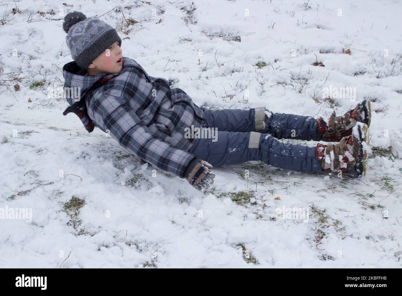 winter holidays are happy, the boy rides from the hills on his back Stock Photo