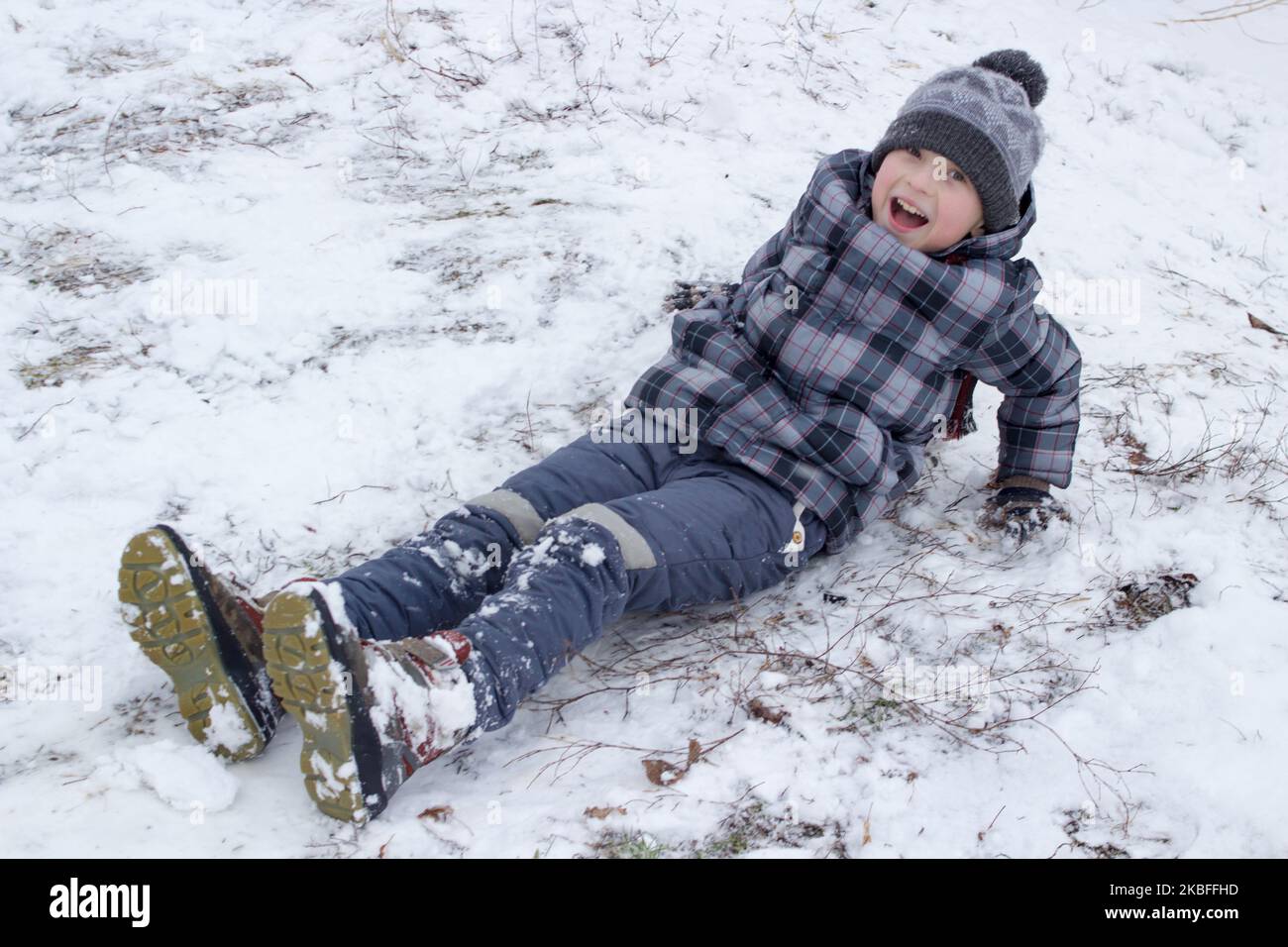 happy boy riding in the buttocks from the hill in the snow Stock Photo