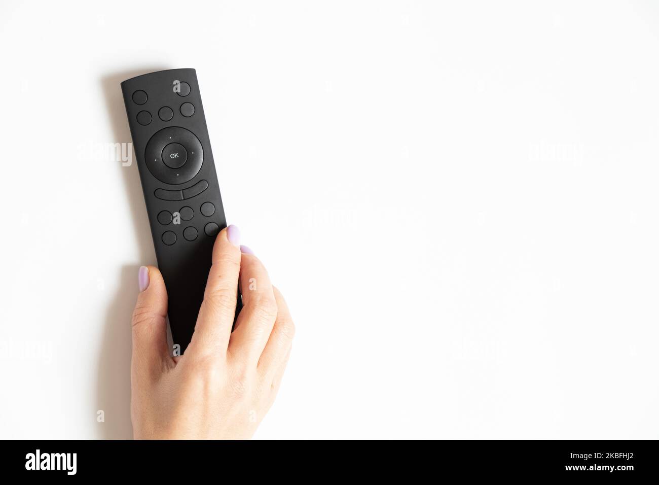Remote control in a female hand on a white background close-up, TV remote control Stock Photo