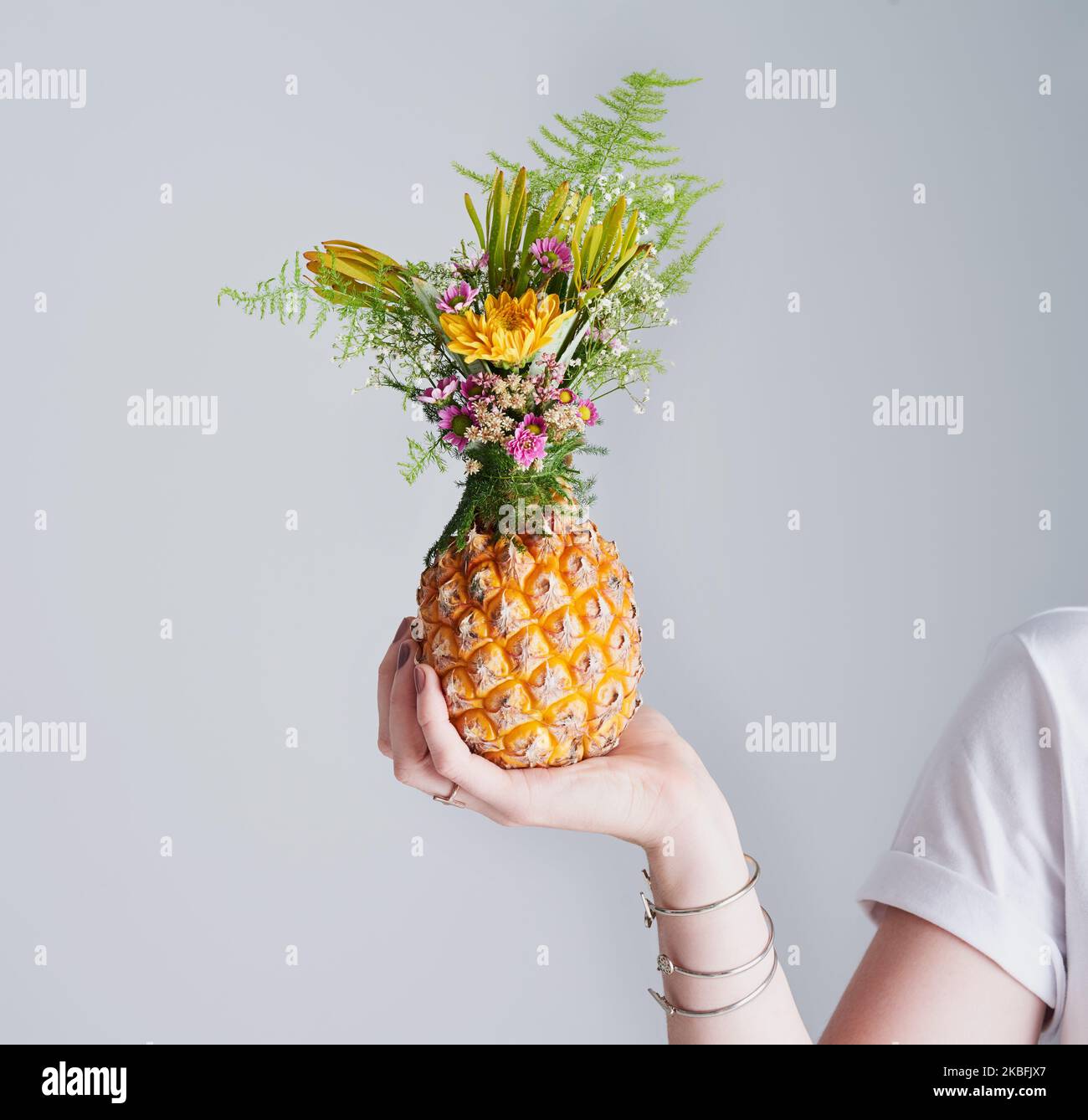 My crown is decorated and beautiful. Studio shot of an unrecognizable woman holding a pineapple against a grey background. Stock Photo