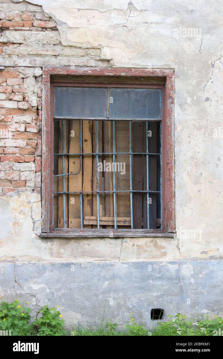 Old stonemade window with bars and barbed-wire on it Stock Photo
