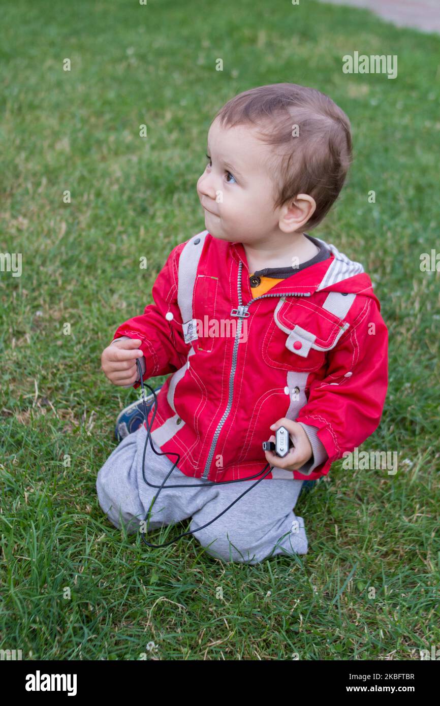 little boy sitting on his knees on the grass Stock Photo Alamy