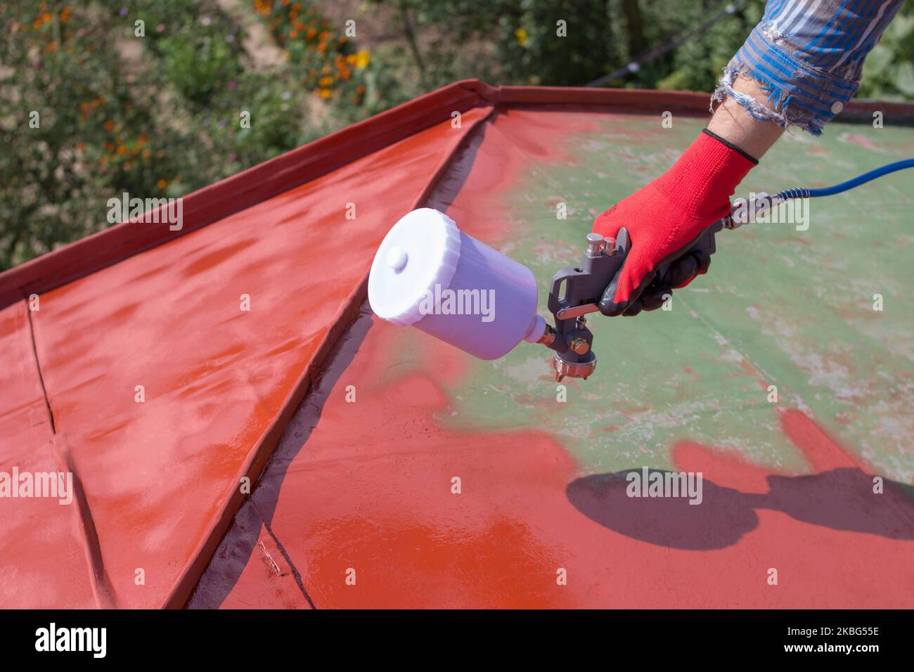 the hand holds the sprayer and paints the roof Stock Photo