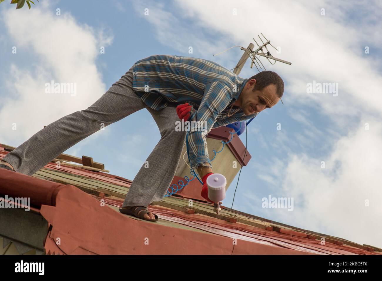 roofer builder worker with pulverizer spraying primer before the roof Stock Photo