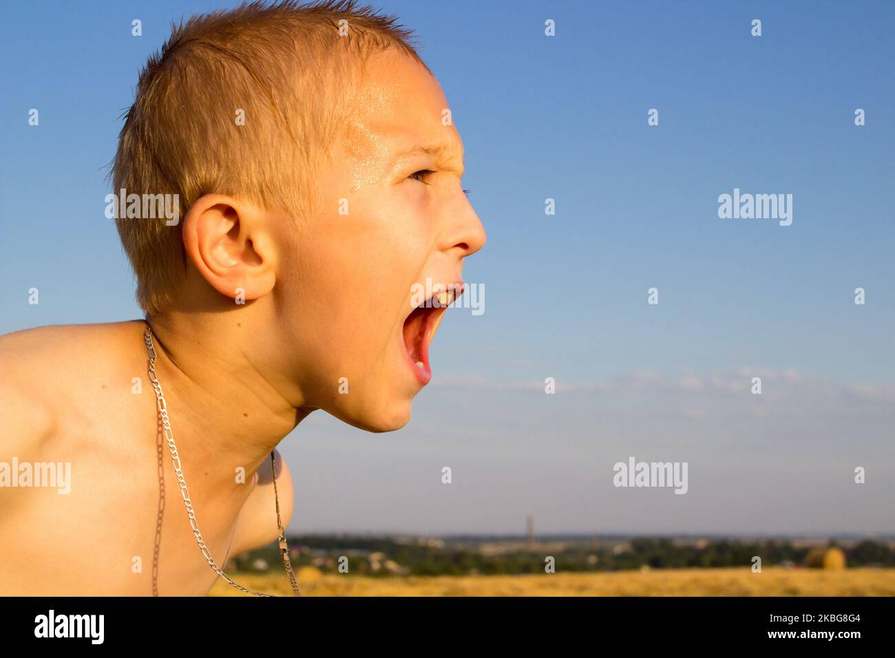 Boy screaming at sunset in the summer Stock Photo