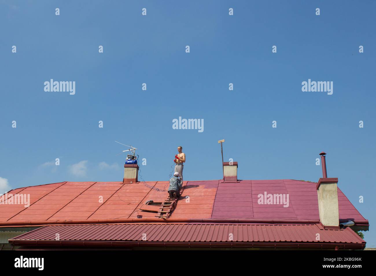 people work on the roof in the summer, an older man and his son paint the roof Stock Photo