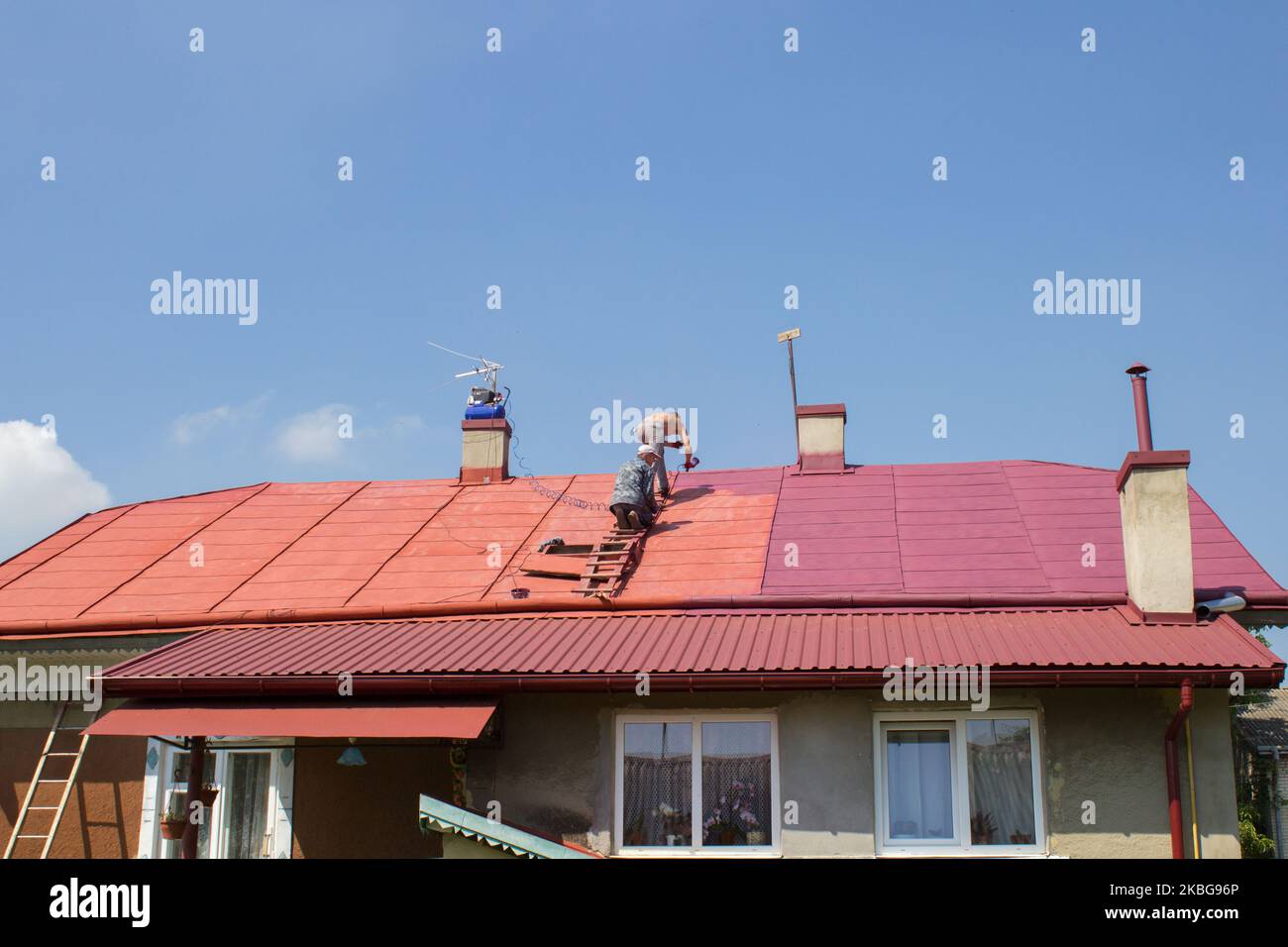 summer, two men painted red roof compressor Stock Photo