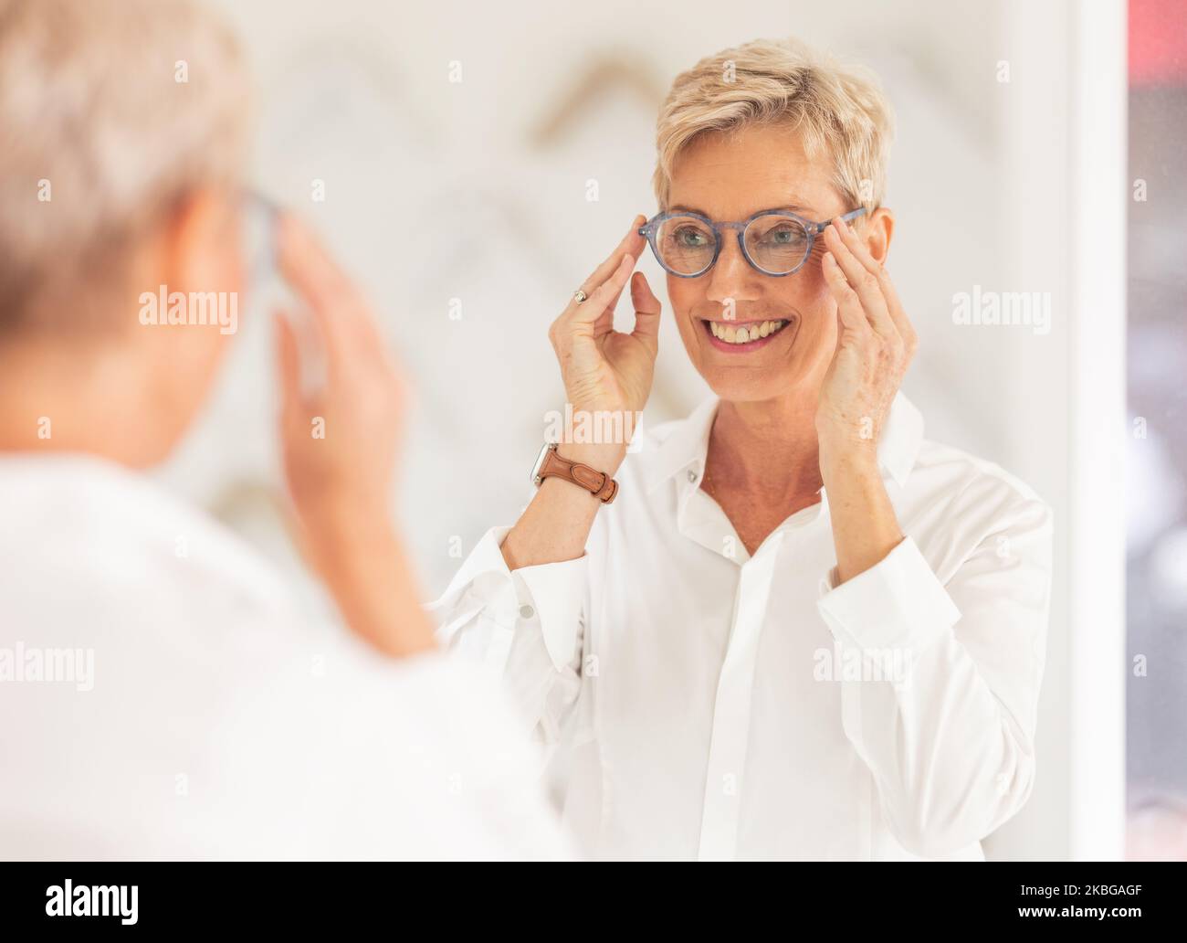Senior woman, smile and mirror for glasses, vision or eyesight at optometry store. Happy elderly female smiling in happiness for new spectacles Stock Photo