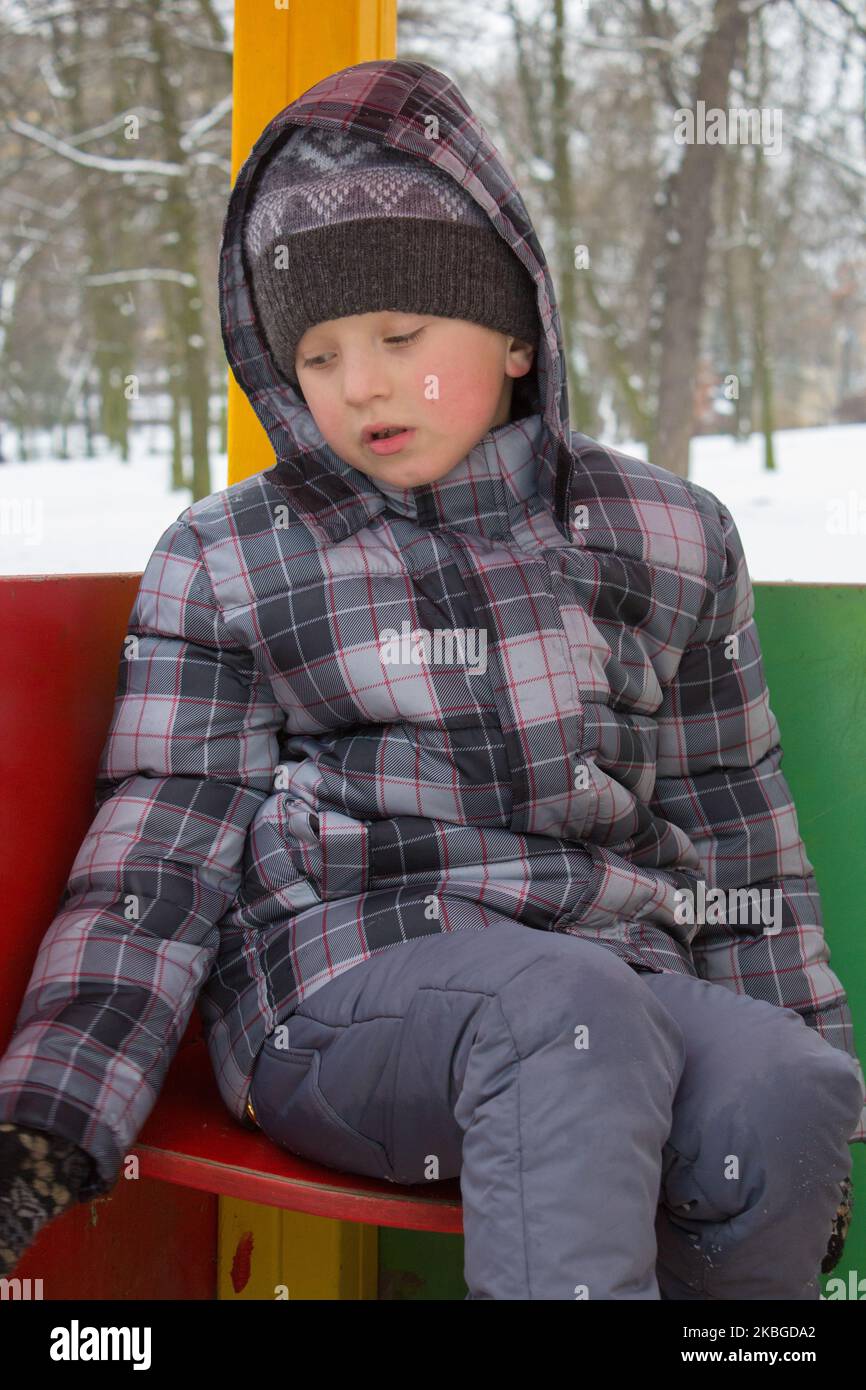 sad boy sitting in the park winter Stock Photo