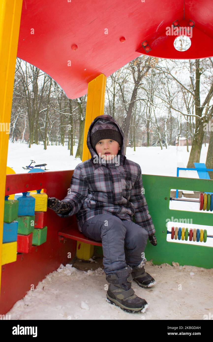 boy sitting in the winter house children's play at the playground in the park Stock Photo