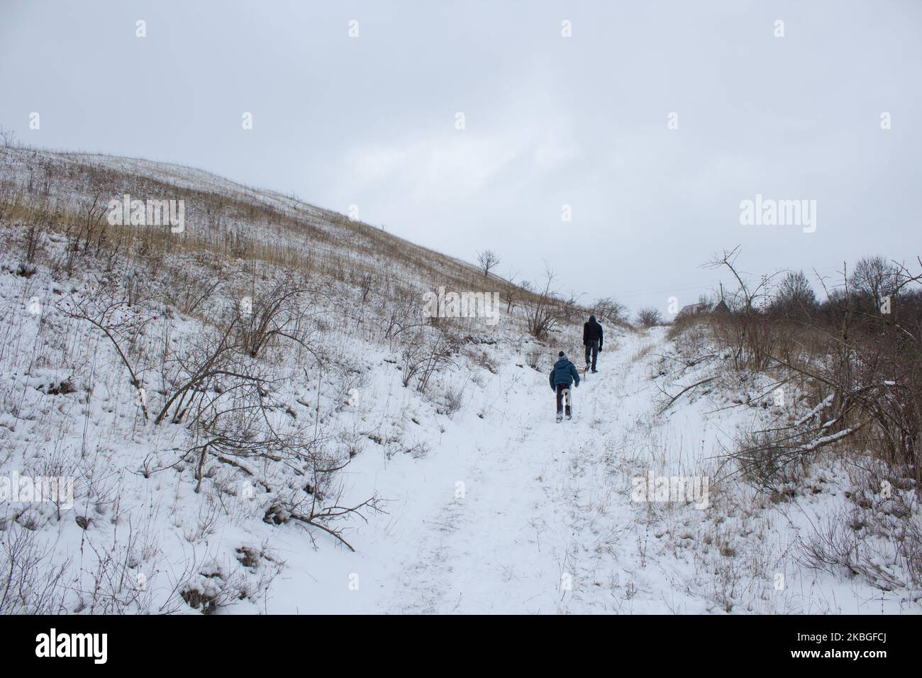 two children go up the mountain in winter with a sled Stock Photo