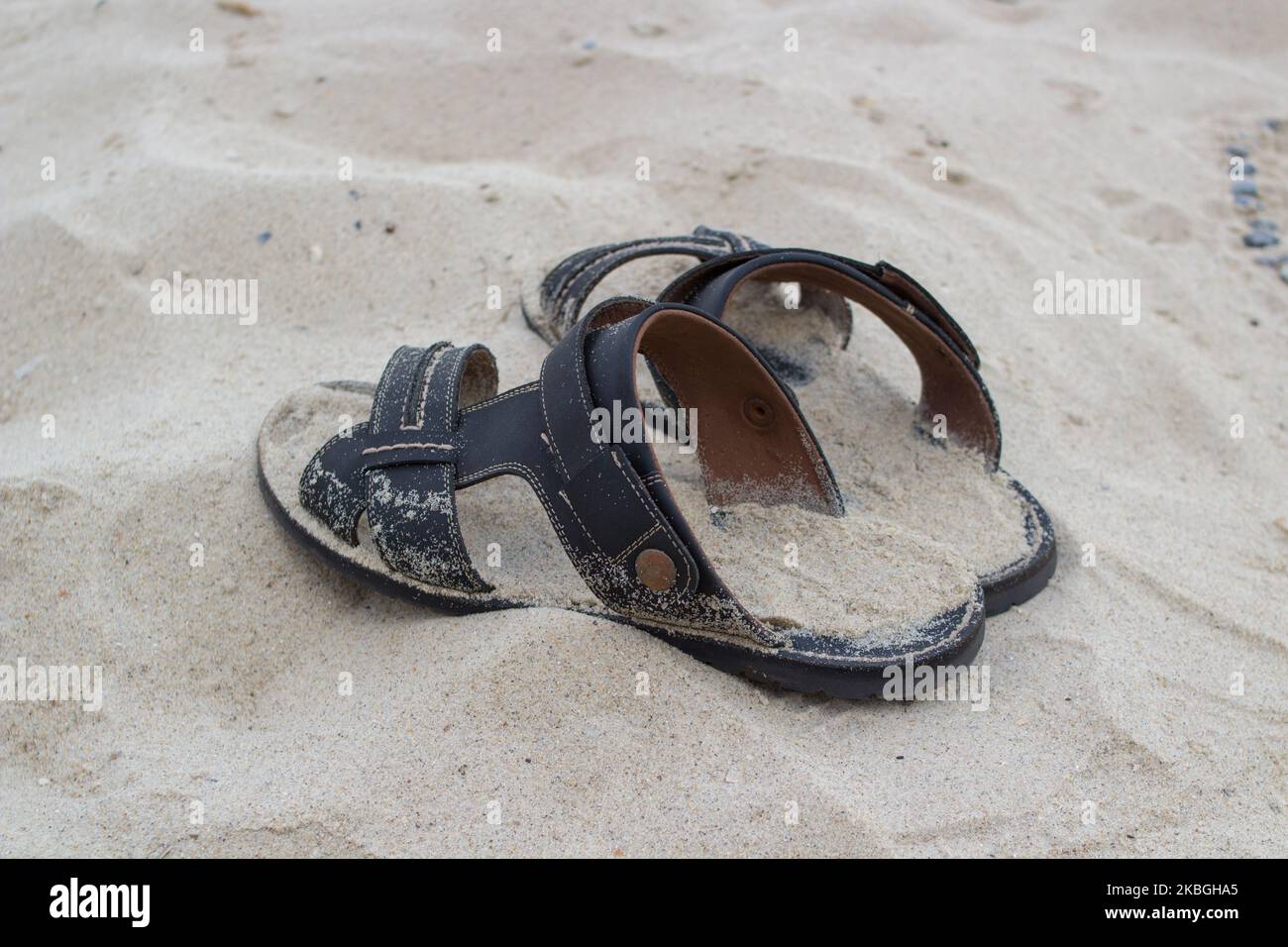 Men's sandals on the sand beach lie on the beach Stock Photo - Alamy