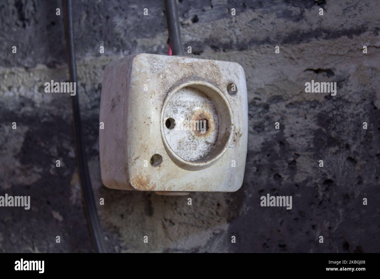 old dangerous electrical outlet on the wall hangs dirty Stock Photo