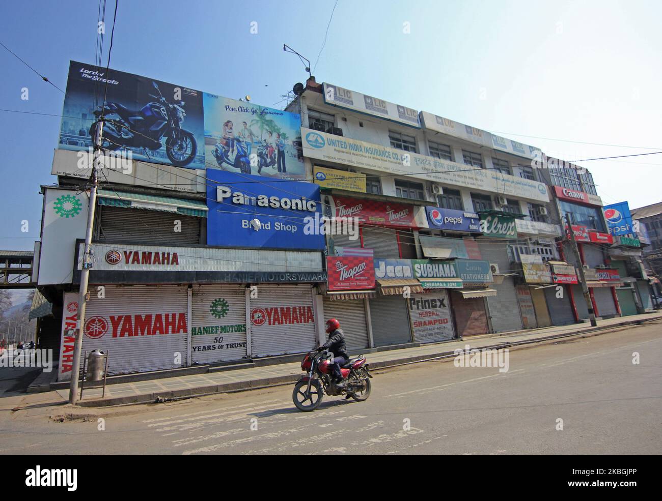A biker moves past closed market during a shutdown in Srinagar on the