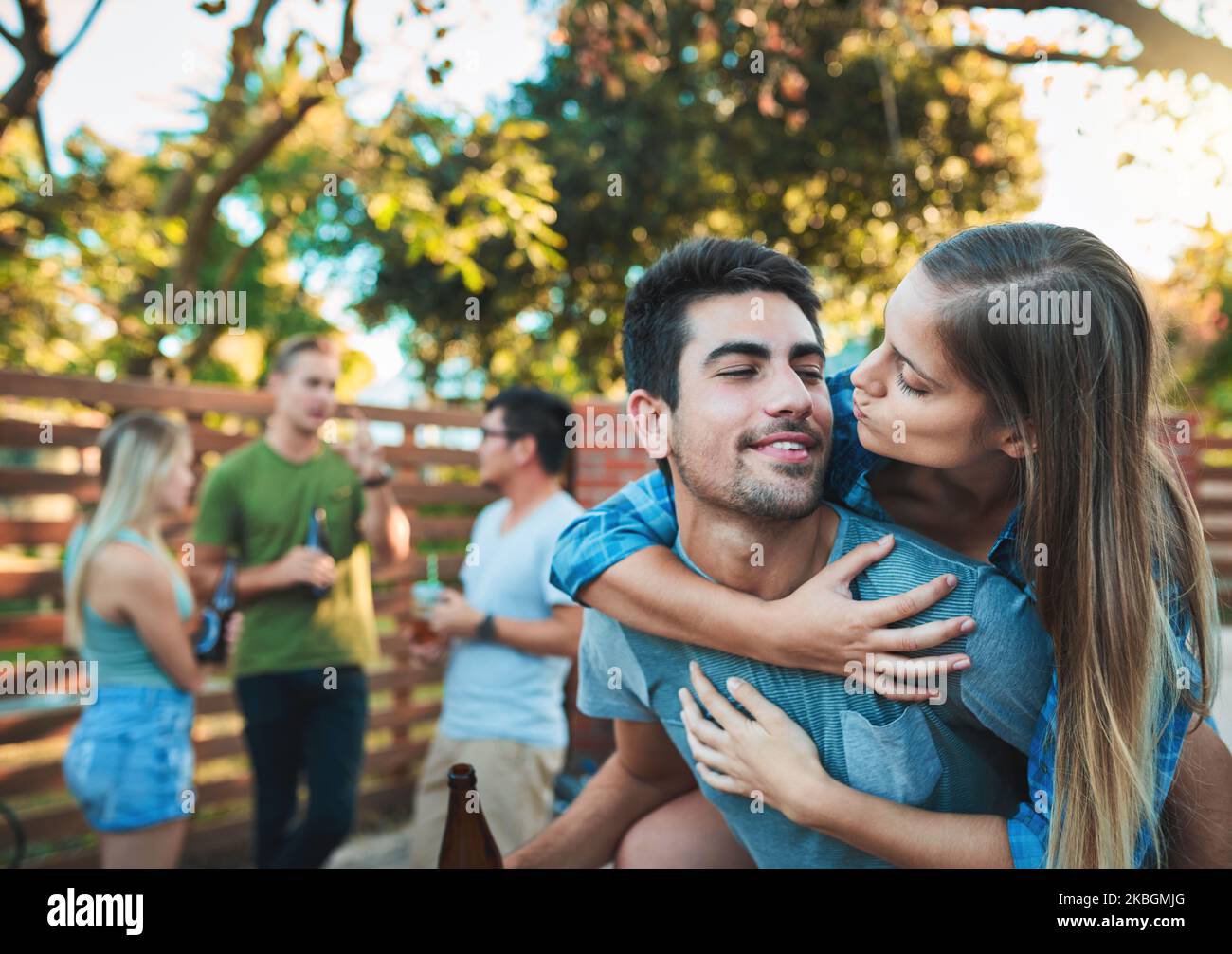 Love puts the we in weekend. a young couple enjoying a piggyback ride while hanging out with their friends. Stock Photo
