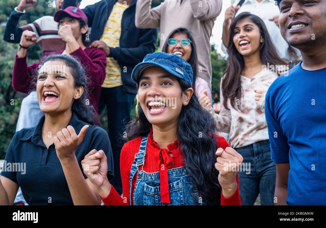 excited girl with audience at stadium cheering by celebrating win by shouting while watching live cricket sports match - concpet of happiness Stock Photo
