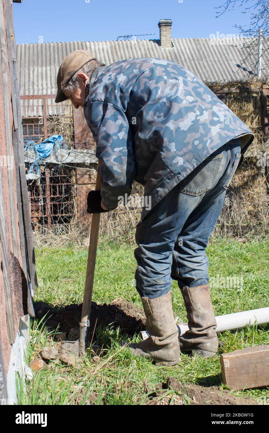 gray-haired grandfather works in the country with a shovel Stock Photo