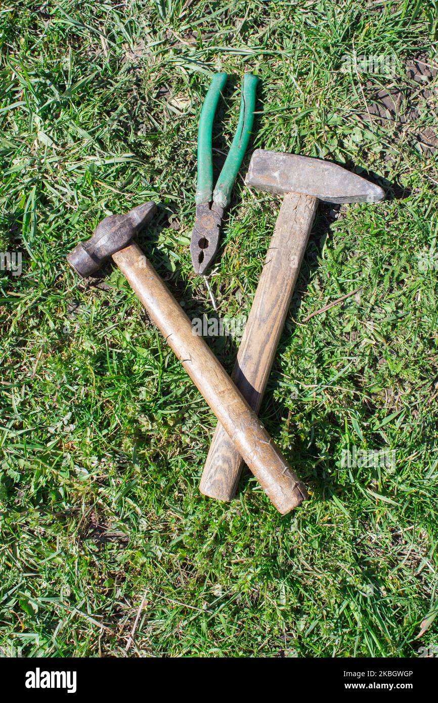 lying on the grass hammer and pliers Stock Photo
