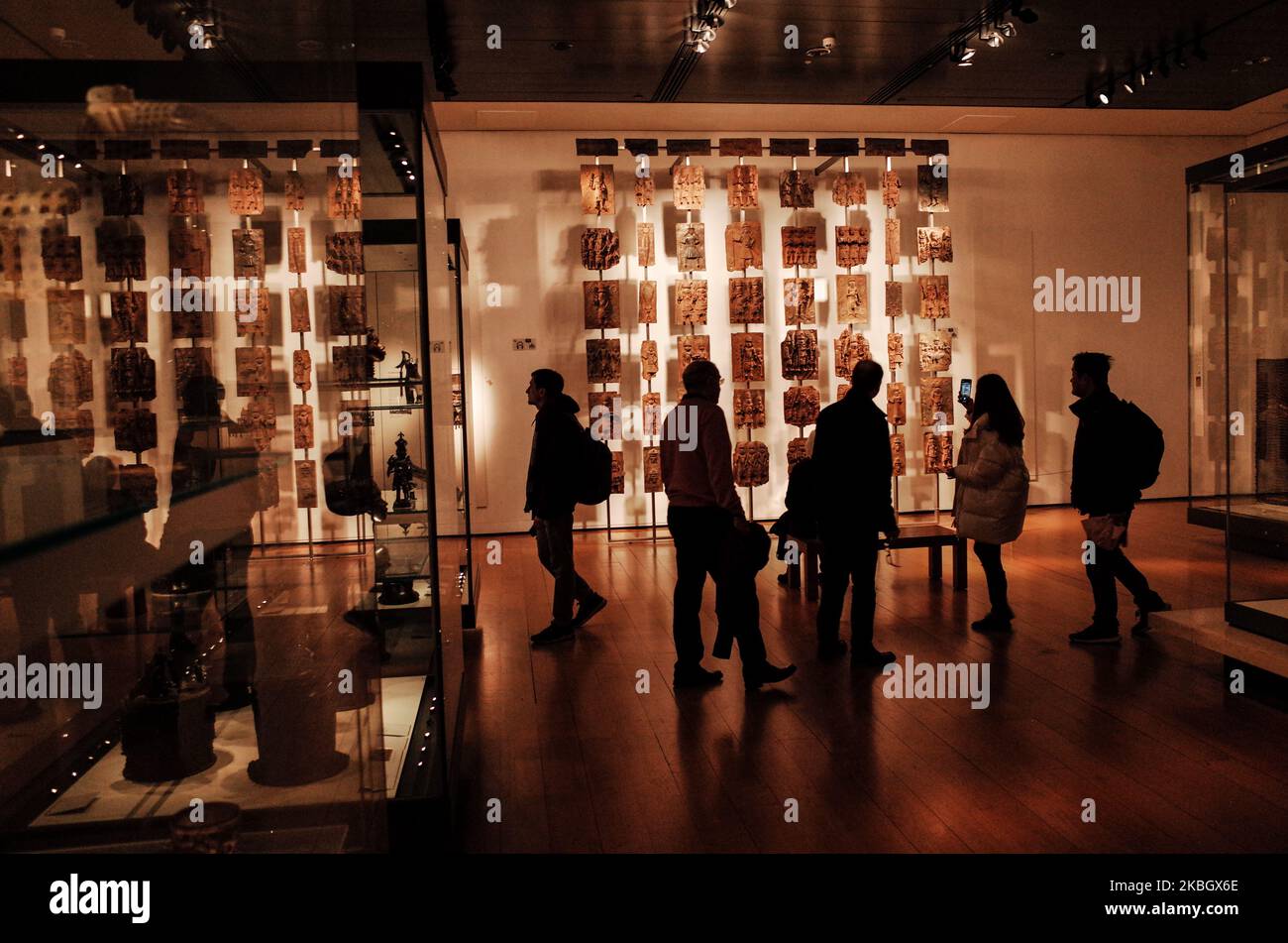 Visitors view the contentious Benin plaques exhibit (more commonly known as the Benin bronzes) in the British Museum in London, England, on February 13, 2020. The museum, one of London's top tourist attractions, is rarely far from controversy, from its long-running refusal to comply with Greek wishes for repatriation of the Parthenon Sculptures (otherwise known as the Parthenon or Elgin Marbles), to other debates on restitution over artifacts including the Rosetta Stone (taken from Egypt) and Benin bronzes (taken from what is now Nigeria), to more recent pressure from climate activists over th Stock Photo